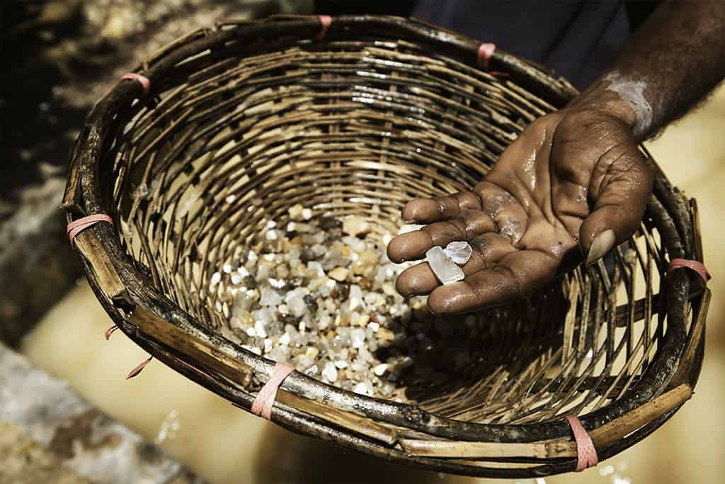 Sri Lankan gem miner washing and inspecting gemstones at a traditional mine